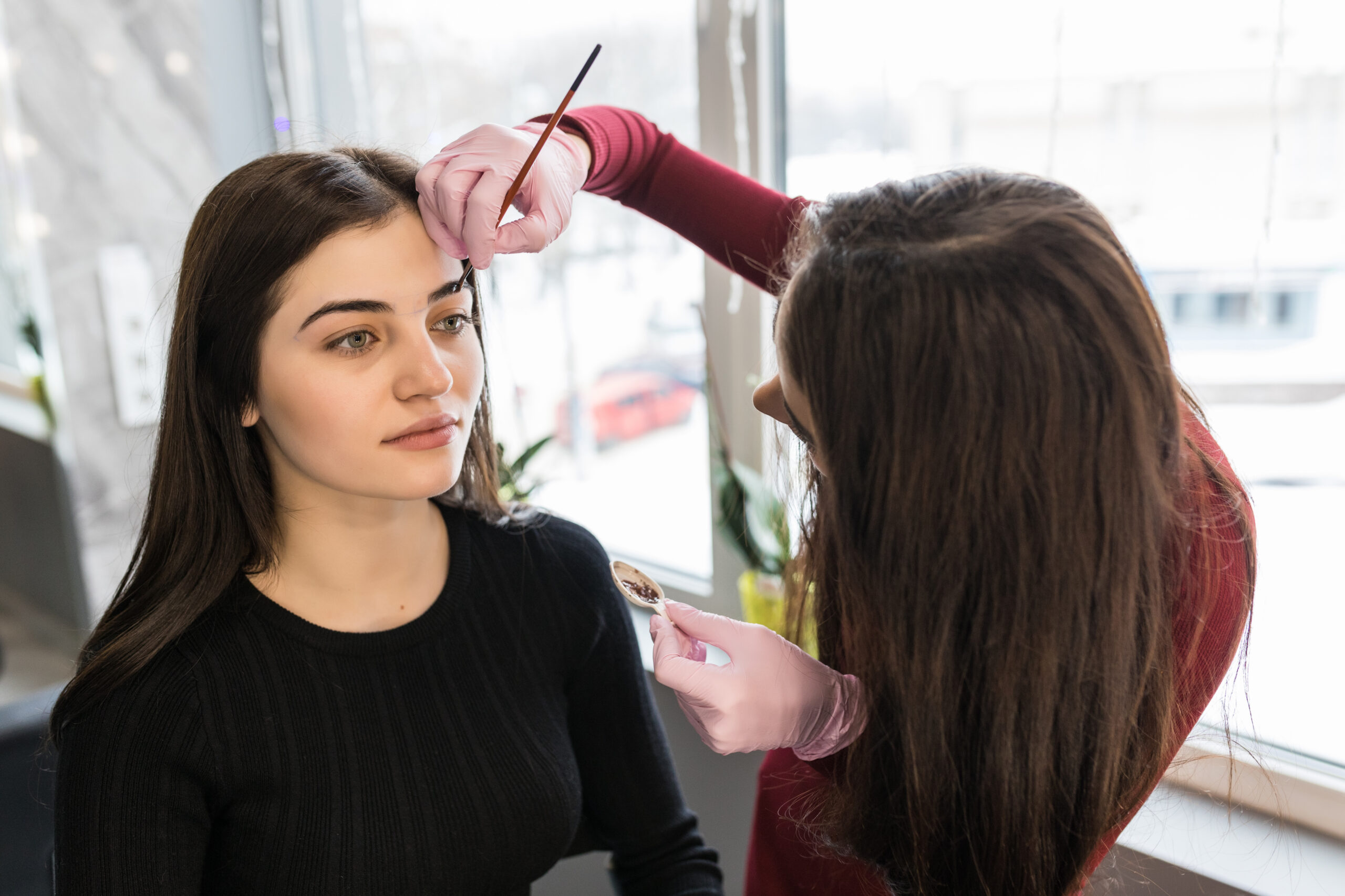 female master put paint with brush during make-up procedure